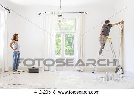 Stock Photo - Couple hanging wallpaper together . Fotosearch