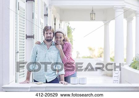 Stock Photo - Couple hugging on porch . Fotosearch