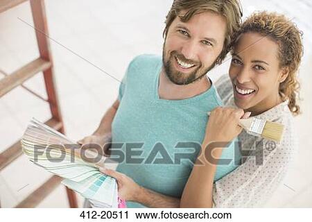 Stock Image - Couple looking through paint swatches together . Fotosearch
