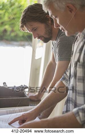 Father and son looking through documents together View Large Photo Image Picture - Father and son looking through documents together . Fotosearch