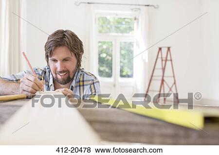 Man marking wood in living area View Large Photo Image Stock Photo - Man marking wood in living area. Fotosearch