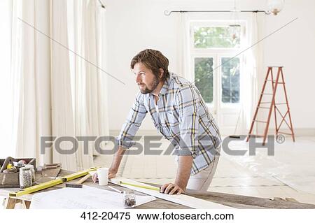 Man overlooking construction table in living space View Large Photo Image Stock Photography - Man overlooking construction table in living space . Fotosearch