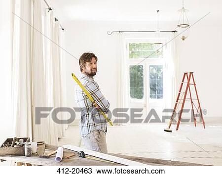 Stock Image - Man overlooking living space near construction materials. Fotosearch