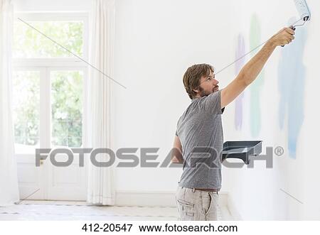 Man painting wall in living space View Large Photo Image Stock Photo - Man painting wall in living space. Fotosearch