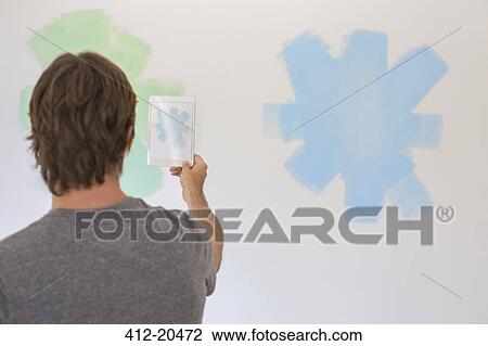 Man taking photo of wall with digital tablet View Large Photo Image Stock Image - Man taking photo of wall with digital tablet . Fotosearch