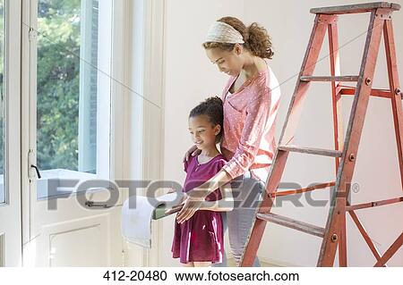 Stock Image - Mother and daughter looking through binder together . Fotosearch