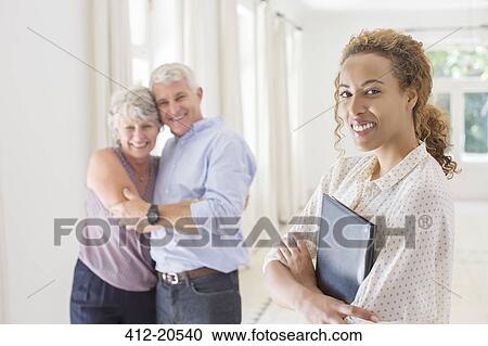 Stock Image - Older couple hugging with woman smiling . Fotosearch