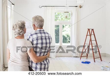 Stock Image - Older couple looking at construction plans together. Fotosearch