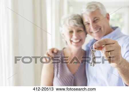Stock Image - Older man holding keys with wife . Fotosearch