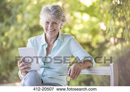 Stock Photo - Older woman using digital tablet outdoors. Fotosearch