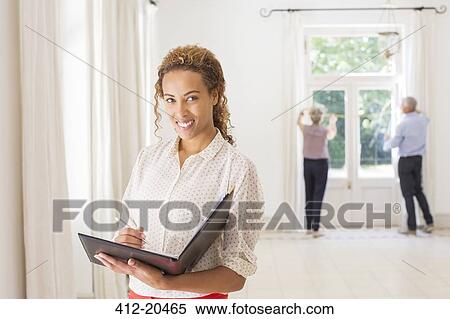Woman holding binder in living space View Large Photo Image Stock Photography - Woman holding binder in living space. Fotosearch