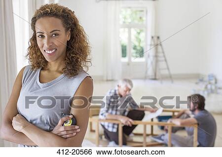Stock Photograph - Woman smiling in living space in family working. Fotosearch