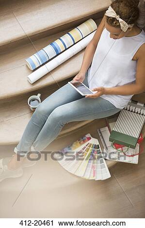 Woman using digital tablet on stairs surrounded by wall paper and color swatches View Large Photo Image Stock Image - Woman using digital tablet on stairs surrounded by wall paper and color swatches. Fotosearch