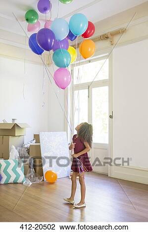 Young girl holding balloons in living space View Large Photo Image Stock Image - Young girl holding balloons in living space . Fotosearch