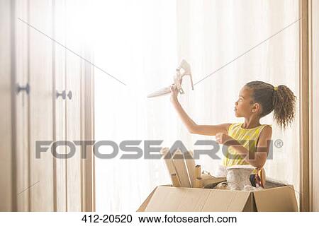 Stock Image - Young girl holding up high heel shoe . Fotosearch