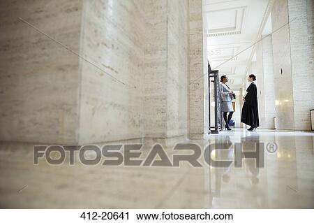 Stock Image - Lawyer and judge talking in hallway of courthouse. Fotosearch