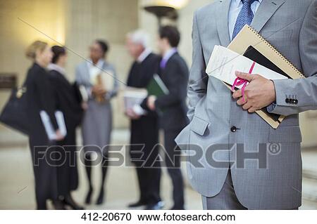 Lawyer holding legal documents in courthouse View Large Photo Image Stock Image - Lawyer holding legal documents in courthouse. Fotosearch