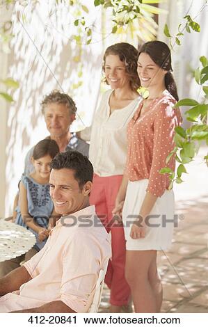 Stock Image - Family gathered around table outdoors . Fotosearch