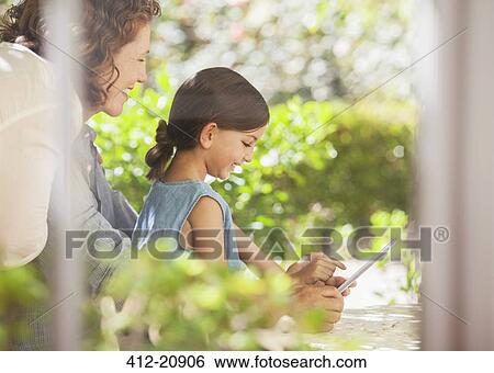 Granddaughter playing on digital tablet with granddaughter View Large Photo Image Stock Photograph - Granddaughter playing on digital tablet with granddaughter. Fotosearch