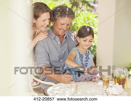 Grandparents playing on digital tablet with granddaughter View Large Photo Image Stock Photo - Grandparents playing on digital tablet with granddaughter . Fotosearch