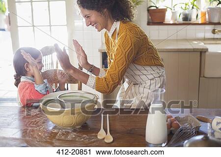 Mother and daughter high fiving in the kitchen View Large Photo Image Stock Image - Mother and daughter high fiving in the kitchen. Fotosearch