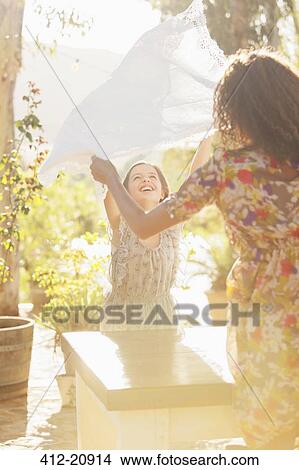 Picture - Mother and daughter laying table cloth on table. Fotosearch