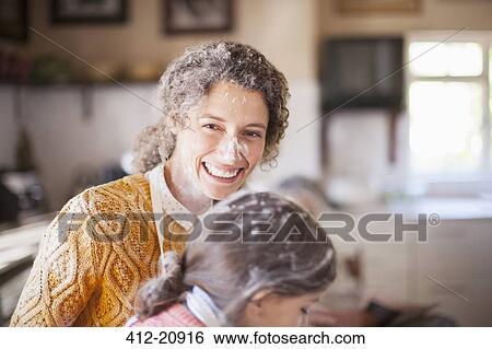 Stock Photograph - Mother and daughter playing with flour in the kitchen. Fotosearch