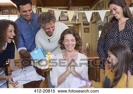 Stock Photography - Older woman being given gift by family. Fotosearch