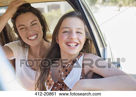 Stock Image - Sisters laughing in car backseat . Fotosearch