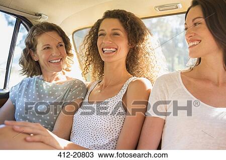 Stock Image - Three women sitting in car backseat together . Fotosearch