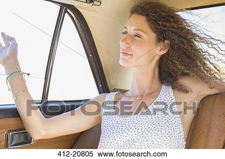 Stock Photography - Woman feeling breeze from backseat car window . Fotosearch