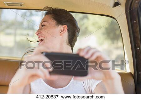 Woman in car backseat taking picture with cell phone View Large Photo Image Stock Photo - Woman in car backseat taking picture with cell phone. Fotosearch