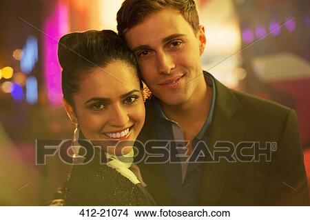 Picture - Couple hugging on city street at night . Fotosearch