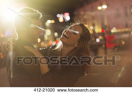 Couple hugging on city street at night View Large Photo Image Stock Image - Couple hugging on city street at night. Fotosearch