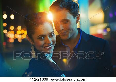 Stock Photo - Couple hugging on city street at night . Fotosearch