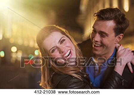 Couple hugging on city street at night View Large Photo Image Stock Photo - Couple hugging on city street at night. Fotosearch
