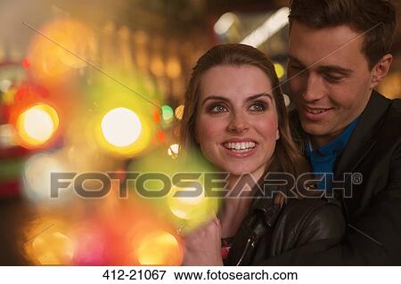 Stock Photo - Couple hugging on city street at night. Fotosearch