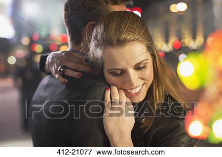 Stock Photo - Couple hugging on city street at night. Fotosearch