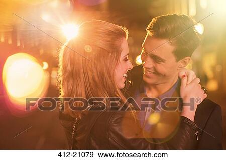Stock Photo - Couple hugging on city street at night. Fotosearch
