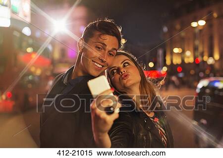Couple taking picture together with cell phone at night View Large Photo Image Stock Photography - Couple taking picture together with cell phone at night . Fotosearch