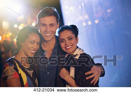 Picture - Friends hugging on city street at night . Fotosearch