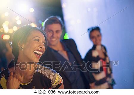 Stock Photograph - Friends laughing on city street at night. Fotosearch