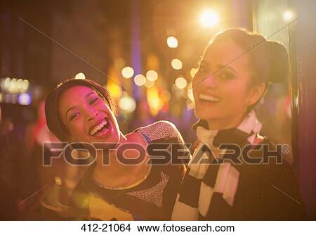 Friends laughing together on city street at night View Large Photo Image Picture - Friends laughing together on city street at night. Fotosearch