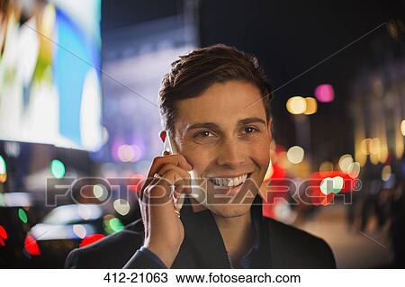 Man talking on cell phone on city street at night View Large Photo Image Stock Image - Man talking on cell phone on city street at night. Fotosearch