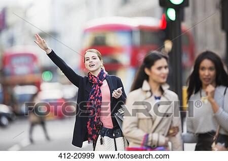 Woman signaling for taxi on city street View Large Photo Image Stock Photo - Woman signaling for taxi on city street . Fotosearch