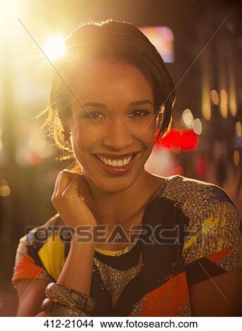 Picture - Woman smiling on city street at night. Fotosearch