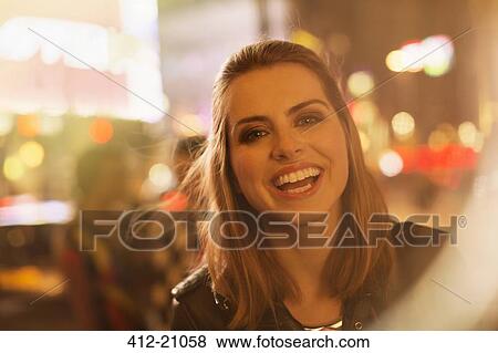 Stock Photo - Woman smiling on city street at night. Fotosearch