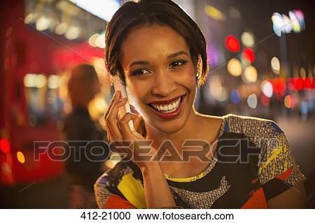 Woman taking on cell phone on city street at night View Large Photo Image Stock Image - Woman taking on cell phone on city street at night . Fotosearch