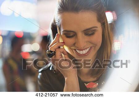 Stock Photo - Woman taking on cell phone on city street at night. Fotosearch