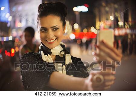 Woman taking picture using cell phone at night View Large Photo Image Stock Photo - Woman taking picture using cell phone at night. Fotosearch